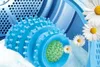 A blue dryer ball with spikes is shown inside a dryer drum, surrounded by white towels and daisies. Anteprima dell’immagine prodotto