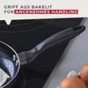A close-up of a frying pan handle on a stovetop, with text overlay describing its features. Produktbild-Vorschau