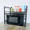 A black microwave oven stand with items on the top shelf, including spice jars, food containers, and a box of tea. Náhľad obrázku produktu