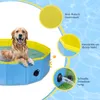 A golden retriever dog is playing in a blue and yellow foldable dog pool. The image includes callouts highlighting product features. Produktbild-Vorschau