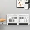 A white radiator cover with a decorative pattern is shown in a room with a gray wall and floor. A yellow chair is partially visible on the left. Produktbild-Vorschau