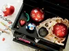 Christmas ornaments and pens are arranged in and around an open black box. Produktbild-Vorschau