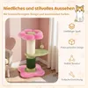 A pink and green cat tree with a flower-shaped base and top, set against a light pink wall and a white curtain. Produktbild-Vorschau