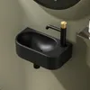 A close-up shot of a black ceramic corner wall-mounted sink with a black faucet with a gold accent. Anteprima dell’immagine prodotto