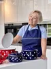 A woman in a kitchen is holding a pot lid, with several polka-dotted pots on the counter. Anteprima dell’immagine prodotto