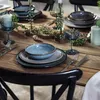 A dining table set for a meal with plates, bowls, glasses, and candles. Produktbild-Vorschau