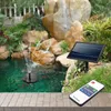 A solar-powered water pump with a remote control is shown operating in a garden pond with a rock waterfall in the background. Podgląd zdjęcia produktu