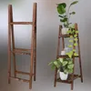 A wooden plant stand is shown in two configurations: one empty and one with plants and decorative items. Produktbild-Vorschau