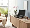 A modern living room with a wooden sideboard, a chair with a blanket, and a balcony view. Produktbild-Vorschau