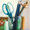 A close-up shot of a Fiskars training scissors and colored pencils in a glass. Voir les images du produit