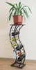 A wine rack with a plant on top, against a light-colored wall. Anteprima dell’immagine prodotto