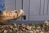 A person's boot is stepping near a gray storage box on the ground with leaves. Náhled obrázku produktu