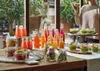 A table laden with various juices, salads in jars, and bowls of soup, set up for a healthy meal or gathering. Produktbild-Vorschau