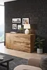 A modern living room with a wooden sideboard against a dark brick wall, decorated with framed pictures and a lamp. Náhled obrázku produktu