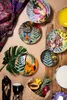 A collection of decorative plates with jungle-themed animal and plant designs, arranged with various decorative and musical items. Anteprima dell’immagine prodotto