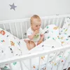A baby sitting in a crib with animal-themed bedding. Produktbild-Vorschau