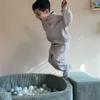 A young boy is jumping into a ball pit filled with colorful balls. Produktbild-Vorschau