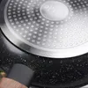 Close-up view of the bottom of a frying pan, showing the textured surface and a portion of the handle. Náhled obrázku produktu