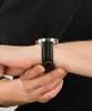 A close-up shot of a person's wrist wearing a black leather-strapped watch. Voir les images du produit