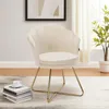 A beige velvet accent chair with gold metal legs is placed on a rug in a room with a framed picture on the wall and a plant in the background. Voir les images du produit