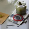 A jar of pickles and related items are arranged on a countertop. Anteprima dell’immagine prodotto