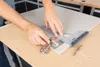 A person is using a measuring tool and a hinge to mark a cabinet door. Voir les images du produit