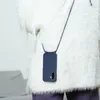 A person wearing a fluffy white sweater and purple pants, with a blue phone case with a lanyard hanging around their neck. Produktbild-Vorschau