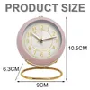 A pink analog alarm clock with dimensions indicated by measurement lines and text. Produktbild-Vorschau