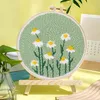 A punch needle embroidery kit with a floral design is displayed on a wooden easel against a yellow background. Produktbild-Vorschau