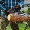 A person is using a chainsaw to cut a log outdoors. Produktbild-Vorschau