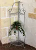 A metal corner shelf with a plant on it, placed in a corner against a stone wall. Podgląd zdjęcia produktu