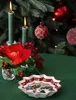 A festive Christmas scene with candles, a poinsettia, and ornaments on a Christmas tree, featuring a decorative bowl in the foreground. Náhled obrázku produktu