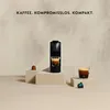A coffee machine with two cups of coffee and coffee capsules, presented on pedestals. Produktbild-Vorschau