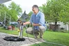 A man is kneeling in a garden, connecting a pump to a hose. Náhľad obrázku produktu