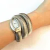 A woman's arm wearing a silver snake-shaped watch. Podgląd zdjęcia produktu