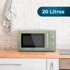A retro-style green microwave oven is displayed on a wooden countertop against a white brick wall. Produktbild-Vorschau