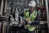 A worker in a hard hat and safety vest is using a DeWALT impact wrench on a large industrial valve and pipe. Podgląd zdjęcia produktu