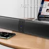 A soundbar speaker is placed on a wooden table next to a smartphone and a laptop. Produktbild-Vorschau