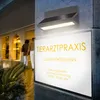 A sign for a veterinary practice is illuminated by a modern outdoor light fixture. Produktbild-Vorschau