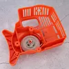 An orange plastic recoil starter assembly is shown on a gray, textured surface. Náhľad obrázku produktu