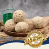 Bird food balls are displayed on a wooden plate with some dried mealworms scattered around. Produktbild-Vorschau