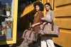 Two women are posing with leopard print bags in front of a yellow shipping container. Náhled obrázku produktu
