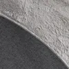 Close-up view of the underside and edge of a round rug, showing the backing material and the fluffy top surface. Voir les images du produit