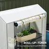 A close-up view of a white greenhouse with a roll-up door and shelves holding plants. Produktbild-Vorschau