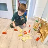 A young boy is playing with a wooden toy tool set on a wooden floor. Anteprima dell’immagine prodotto