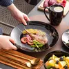 A person is serving a meal on a black marble-patterned plate. Náhľad obrázku produktu