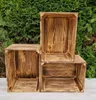 Three wooden crates are arranged in front of a green hedge. Produktbild-Vorschau