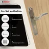 A door handle set with included accessories displayed on a wooden door. Produktbild-Vorschau