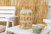 A drink dispenser with sliced fruit sits on a white table, with a white chair and a bamboo screen in the background. Náhled obrázku produktu