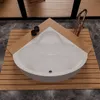 A white corner bathtub with a gold faucet and two black knobs, placed on a wooden slatted platform on a marble floor. Voir les images du produit